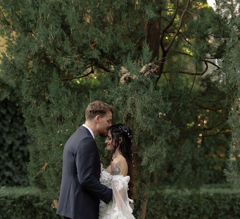 Groom kisses his bride who wears off-the-shoulder sweetheart neckline Pronovias wedding dress with removable sheer sleeves 