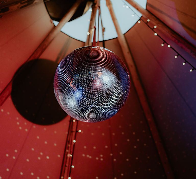 Disco ball wedding decor hangs within tipi 