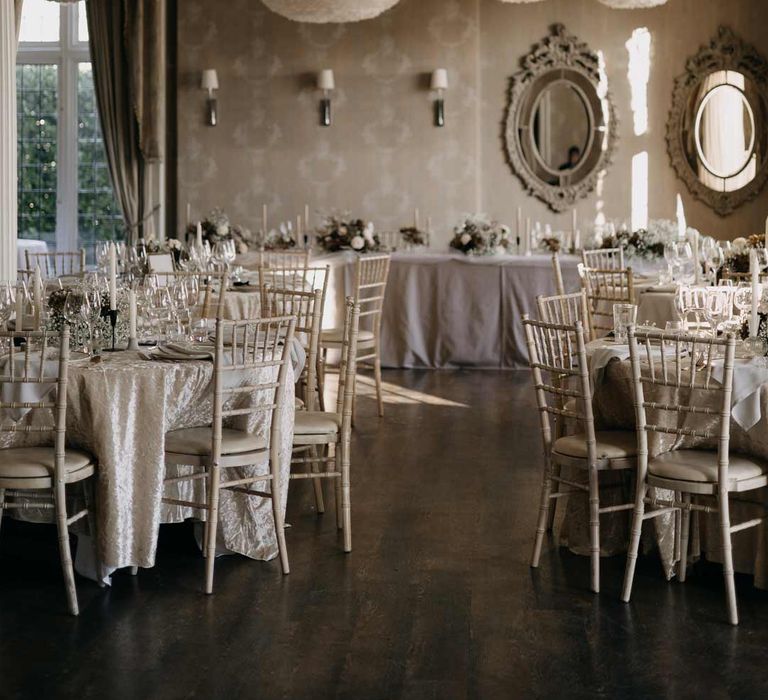 Elegant Manor House wedding reception room with clean, soft neutrals, large artistic lights and dramatic mirrors 