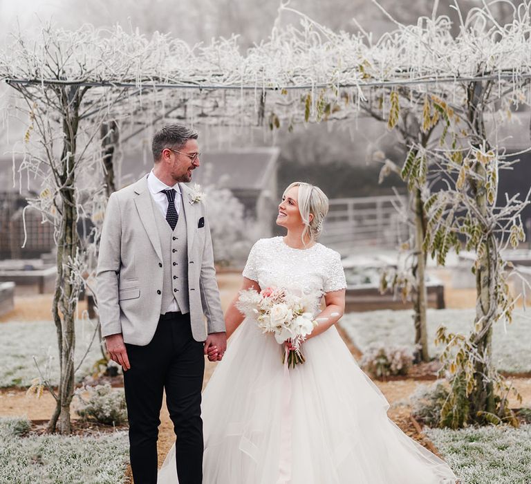 Bride and groom walk hand in hand for their couple portraits at the winter wedding in Hampshire