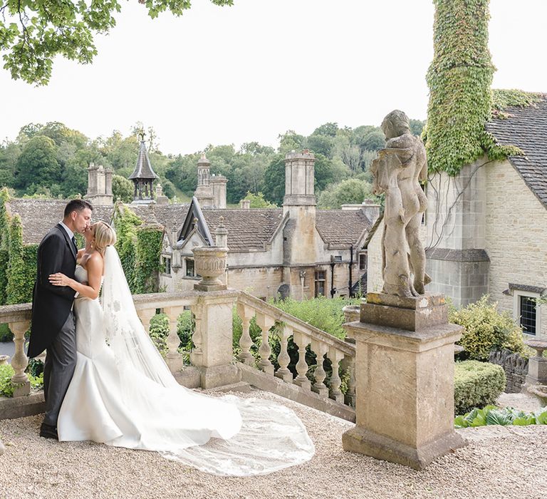 The Manor House, Castle Combe wedding venue with the bride in a mermaid wedding dress and groom in morning suit 