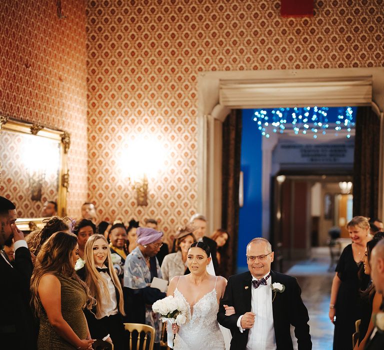 Father of the bride walking bride in sleeveless v neck Enzoani wedding dress with tulle finish and church length veil down the aisle of Grittleton House wedding venue 