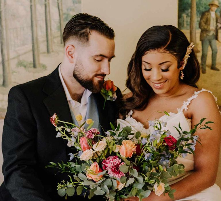 Bride in bow front sleeveless satin wedding dress with large gold bridal hair clip holding large dried flower, eucalyptus, spring florals and garden rose bridal bouquet 