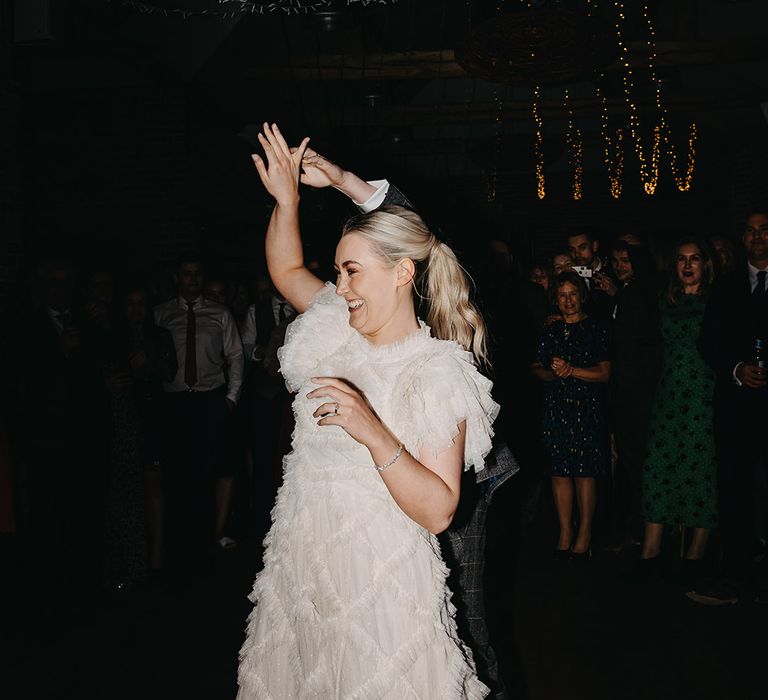 Groom spins the bride around for the first dance wearing a ruffle reception wedding dress 