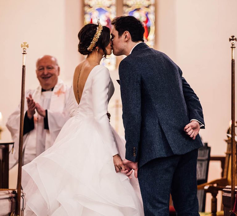 Traditional church wedding in winter with the bride and groom sharing their first kiss as a married couple 