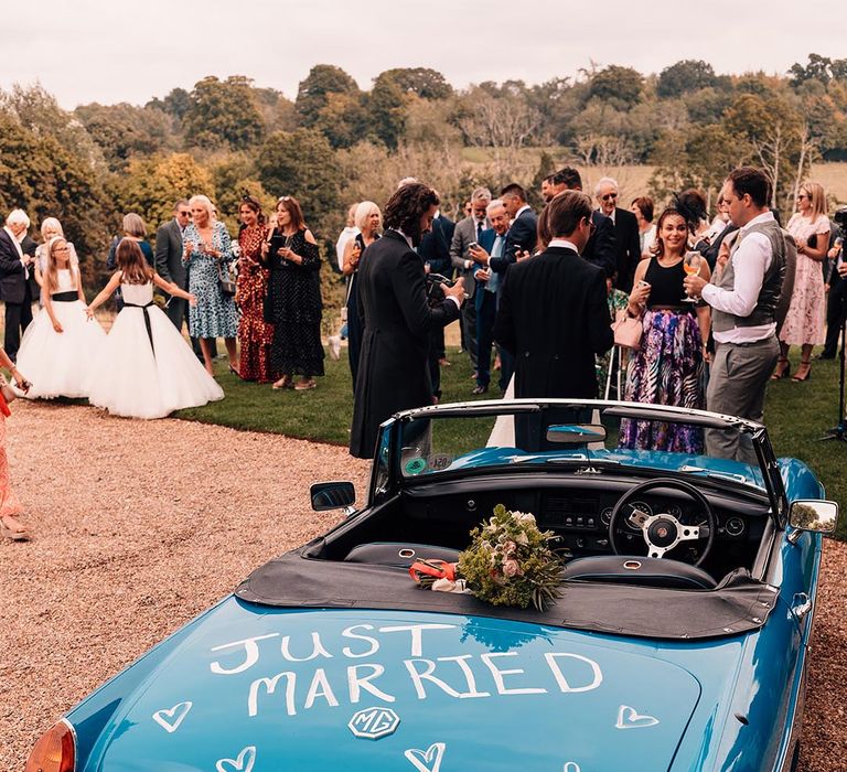 Blue vintage wedding car with pink rose bouquet with 'just married' writing on the back of the car