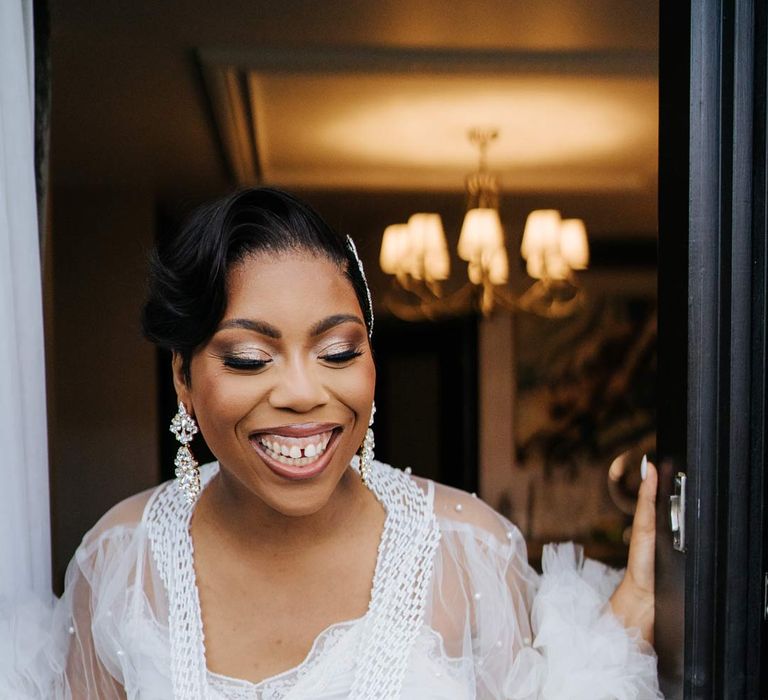 Bride in white sheer tulle and pearl bridal getting ready robe and silver sparkly bridal jewellery 