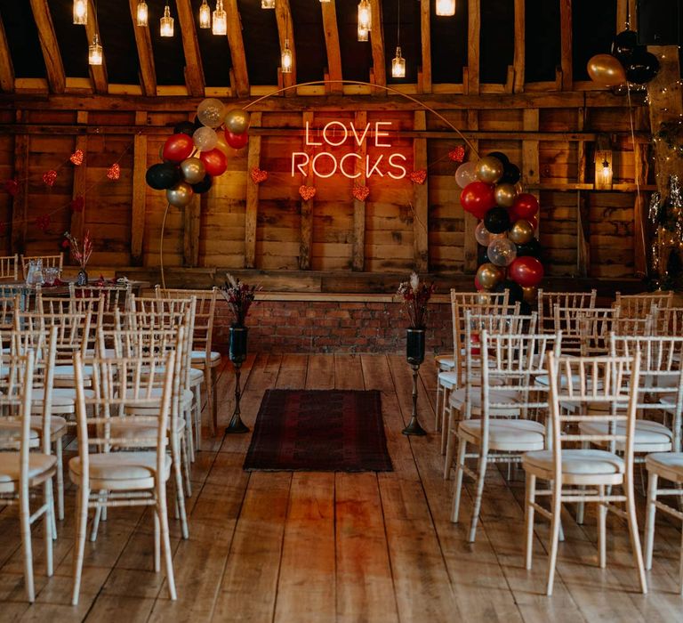 Southlands Barn wedding venue reception room with hanging bottle lights, a balloon wedding arch and a large pink wedding neon light