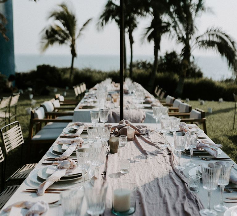 Wedding tablescape with dusty pink runners, glassware and ocean views at outdoor wedding reception