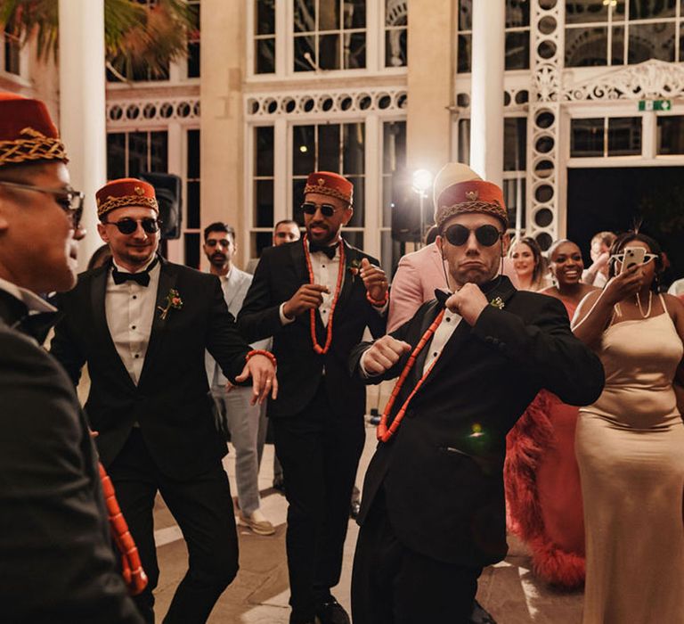 Groomsmen in black tie wearing Kufi hats for Nigerian money dance 