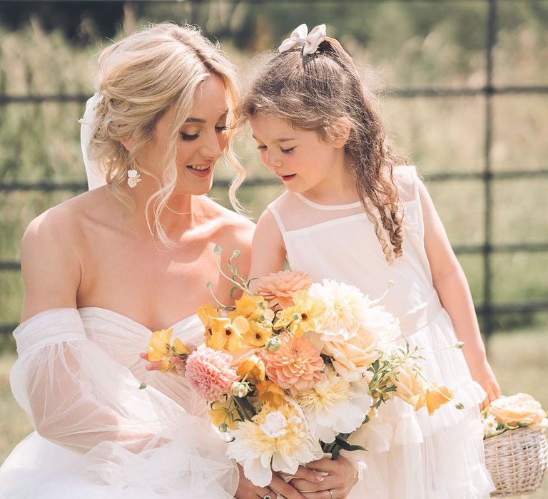 Bride and flower girl looking at yellow wedding bouquet 