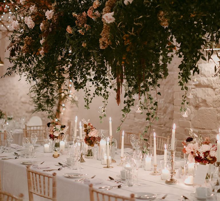 Blush neutral hanging wedding flower installation above table covered in white tablescape 