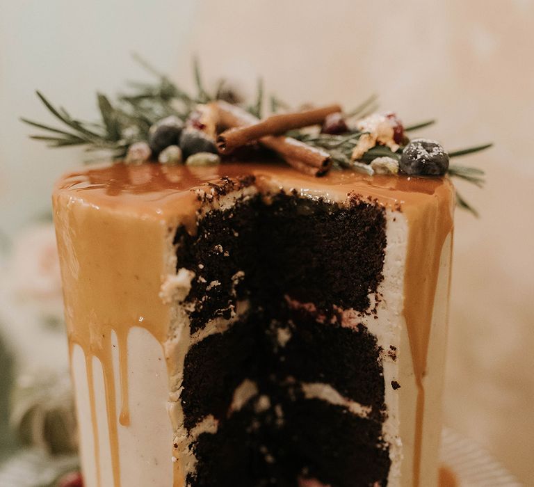 Four tier chocolate sponge wedding cake covered in white icing and drip icing with festive toppers 