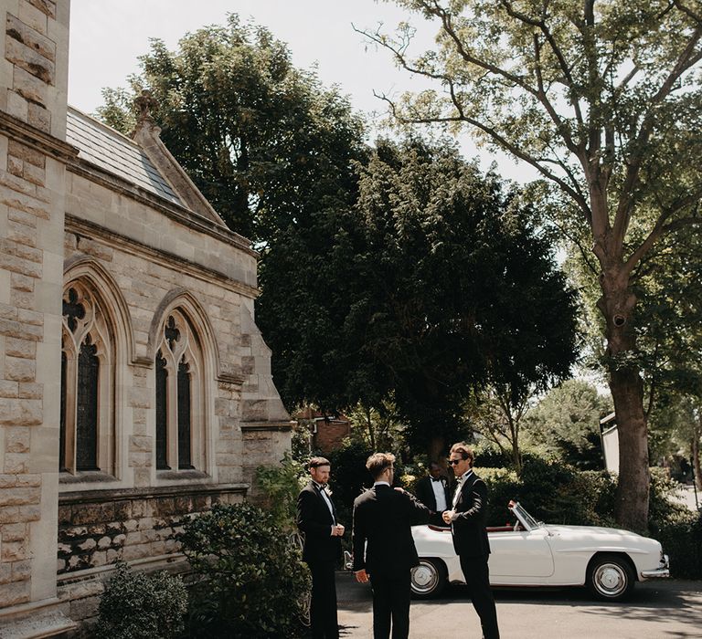 Traditional church wedding ceremony with groomsmen waiting outside for guests to arrive 