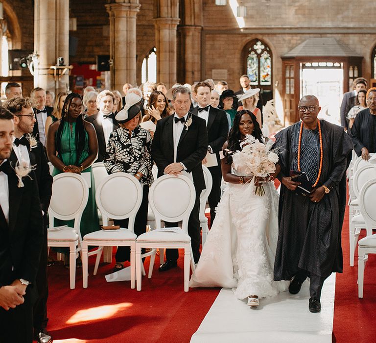 Father of the bride walks the bride down the aisle at traditional church wedding ceremony 