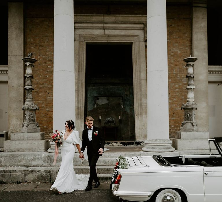 The bride and groom walk to their vintage wedding car 