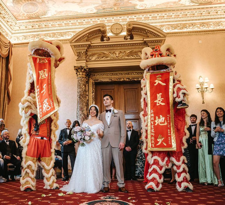 Red and gold Chinese lion dance at traditional Chinese wedding ceremony at Ashridge House 