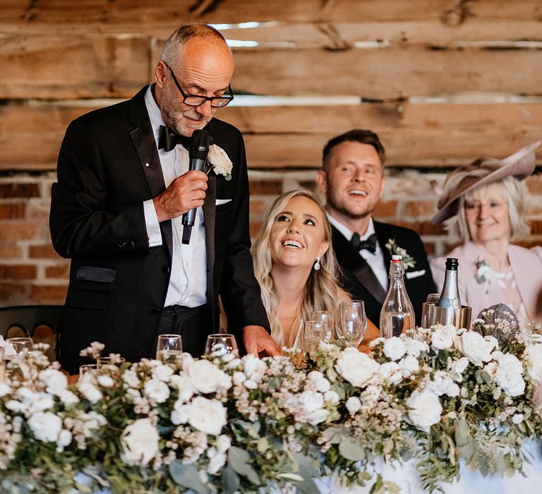 All white wedding flower garland arrangement decorating the top table at the wedding 