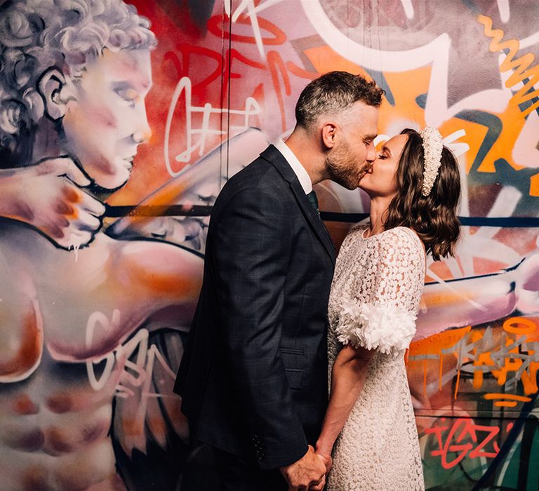 Graffiti backdrop in urban modern city wedding with the bride and groom sharing a kiss