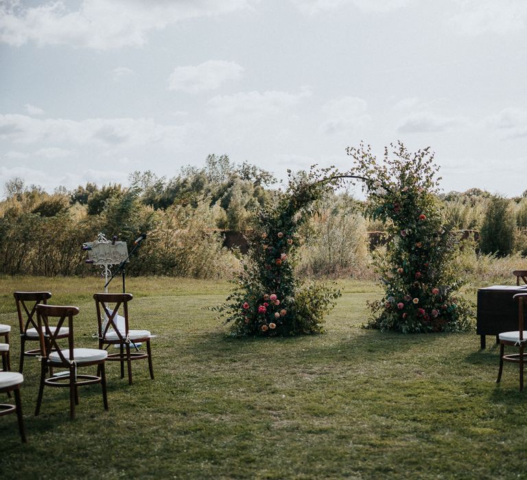 Socially distanced outdoor wedding ceremony at Willow Marsh Farm with floral moon gate altar 