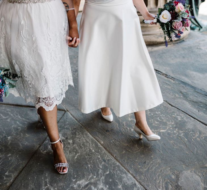 Lesbian brides with white and pink rose wedding bouquets and striking wedding shoes