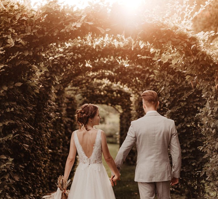 Bride with dried flower wedding bouquet walking through garden with groom