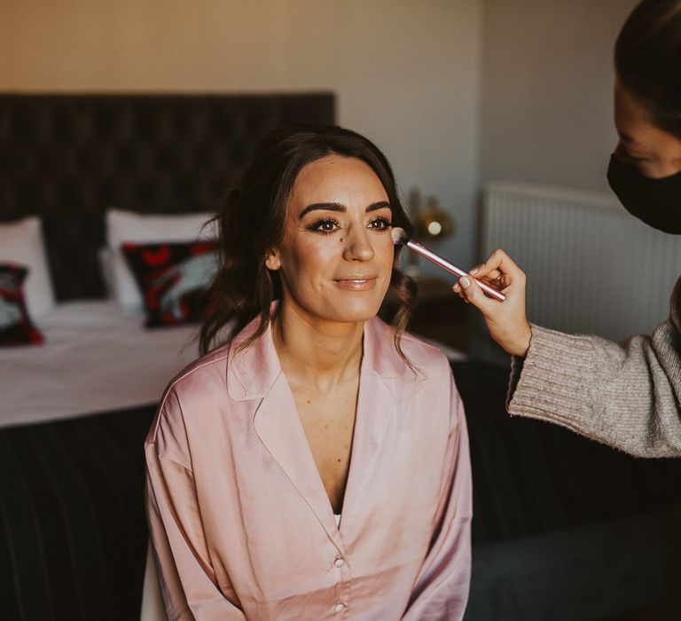 Brown haired bride has her makeup done on wedding morning