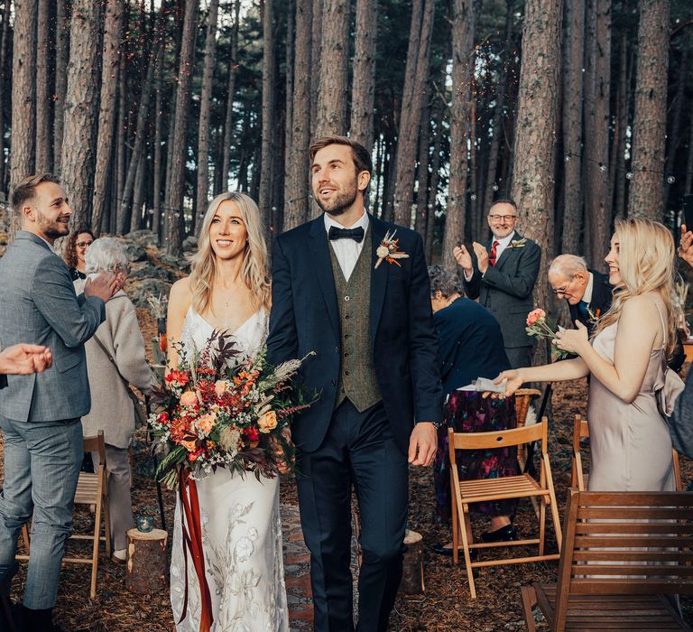 Bride & groom walk through woodland after wedding ceremony