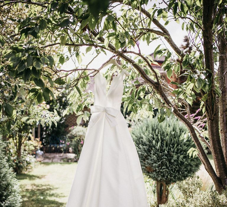 Jesus Peiro wedding dress with front bow hanging in a tree 