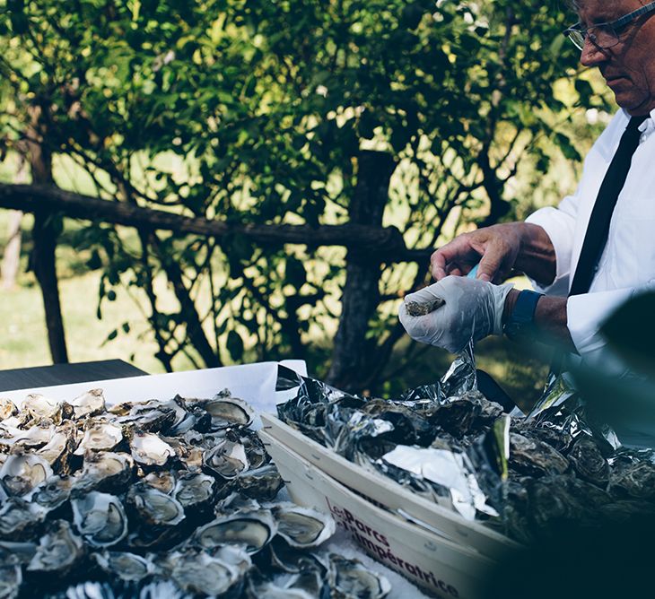 A man is preparing oysters ready to be eaten. The oysters are in a crate.