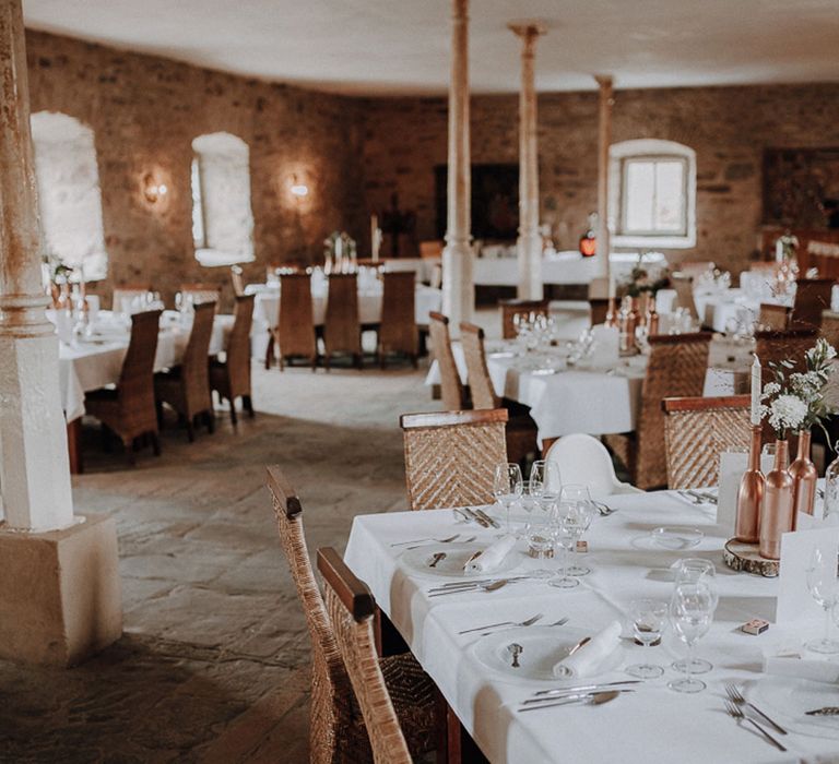 Rustic elegant wedding table decor with rose gold bottle details and rattan chairs at German wedding