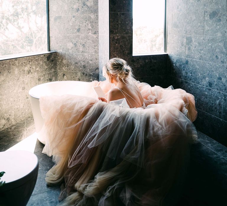 Tulle skirt wedding dress for bride sat in bath for photo