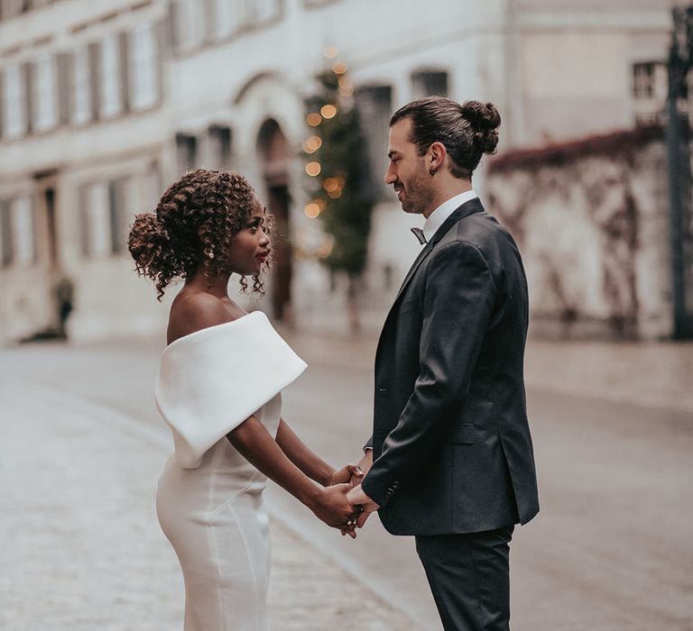 Bride & groom stand together in the Old Town of Switzerland whilst holding hands