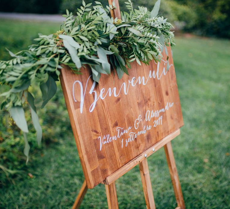 Wooden welcome sign with white calligraphy writing and floral decoration