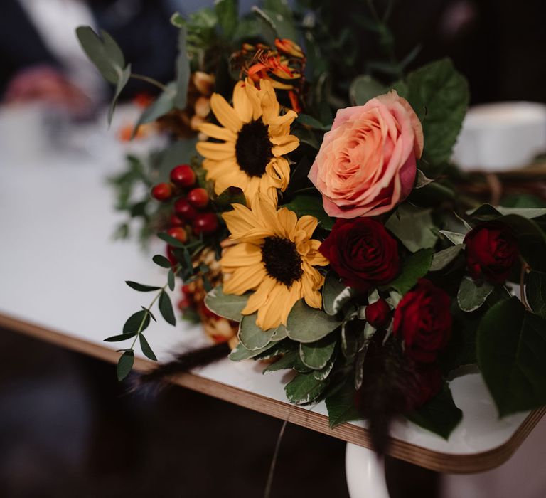 Pink and red rose, yellow sunflower and assorted berry bouquet with leaves