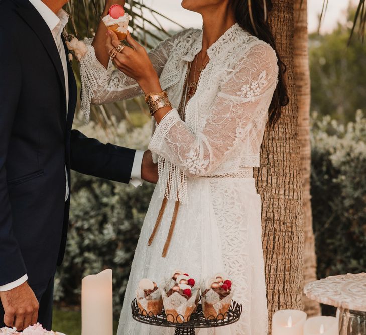 Bride in a lace Marylise Bridal gown with matching jacket eating macaroons 