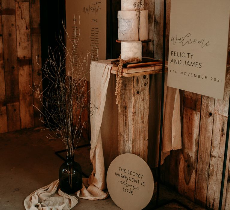 Neutral wedding theme decor with seating chart and welcome sign and cake stand decorated with dried flowers 