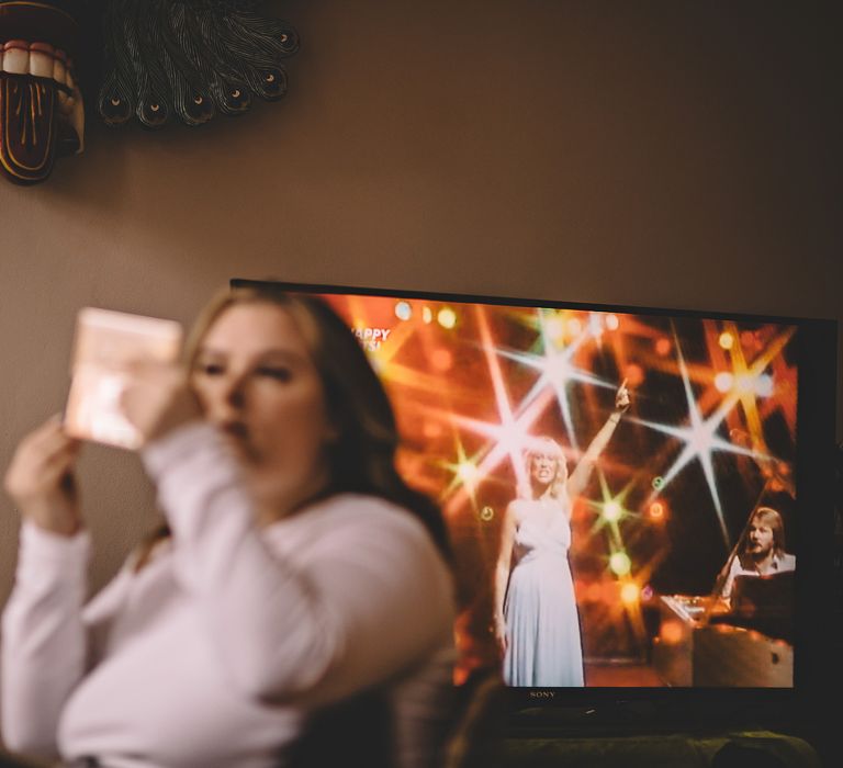 Bride looks in mirror as she applies makeup on the morning of her wedding