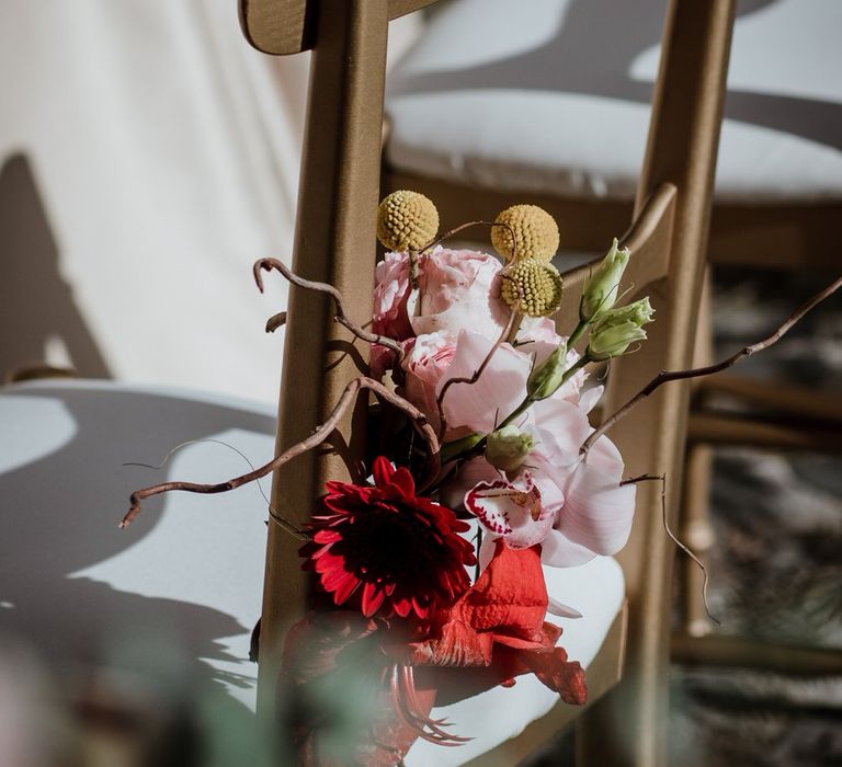 Pink and red flower details on outdoor seating, with pink roses, orchids and red gerberas