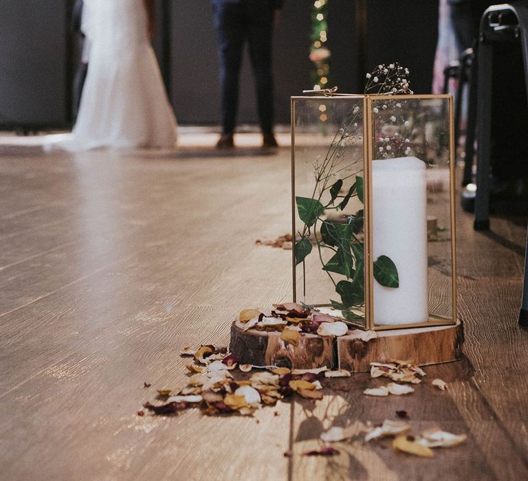 Copper lanterns with a pillar candle resting in a tree stump lining the Heart Church aisle 