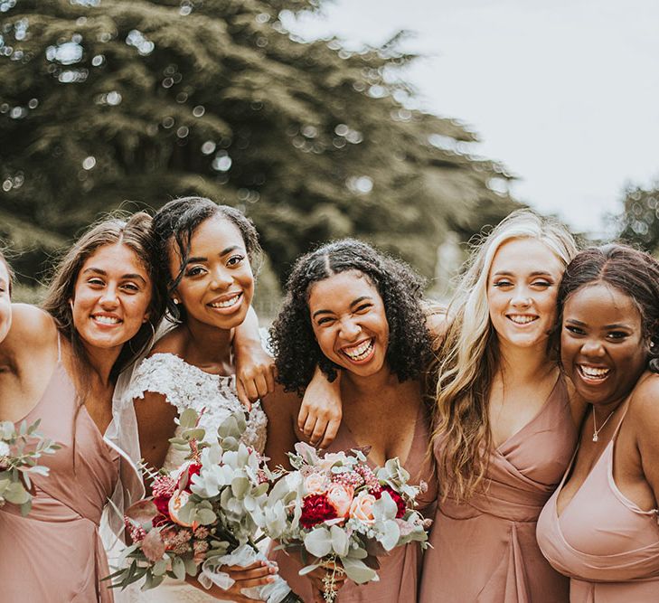 Bridal party portrait with bridesmaids in dusky pink dresses and bride in a lace wedding dress