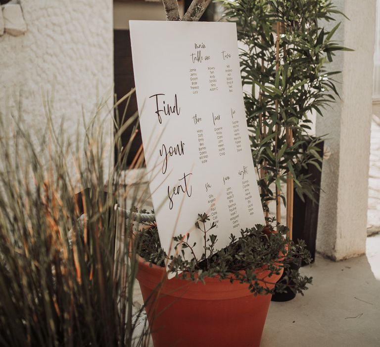 Monochrome wedding table plan decorated with foliage