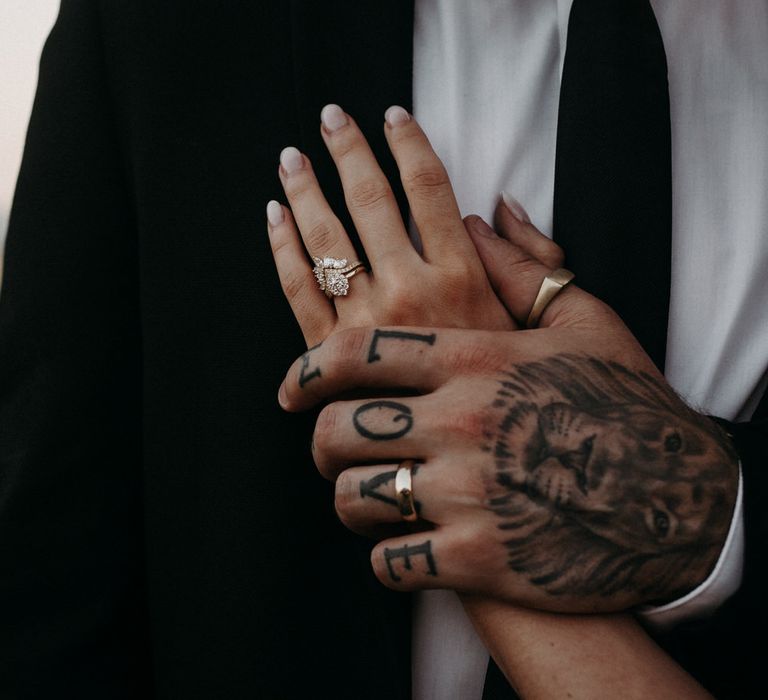 Groom holding the bride's hand against his chest, she is wearing a large diamond ring