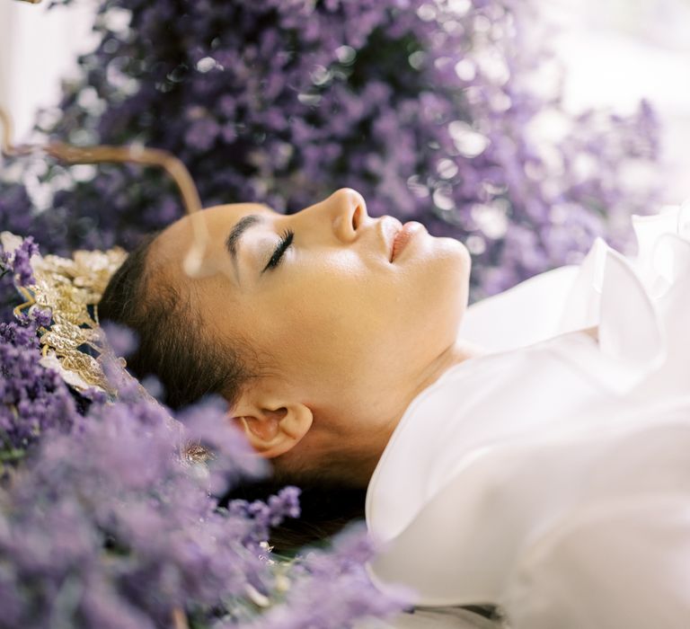 Bride lays within lavender with eyes closed and wearing minimal makeup