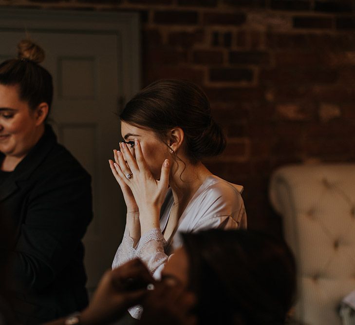 A bridesmaid wipes tears from her eyes as she gets ready for the wedding. 