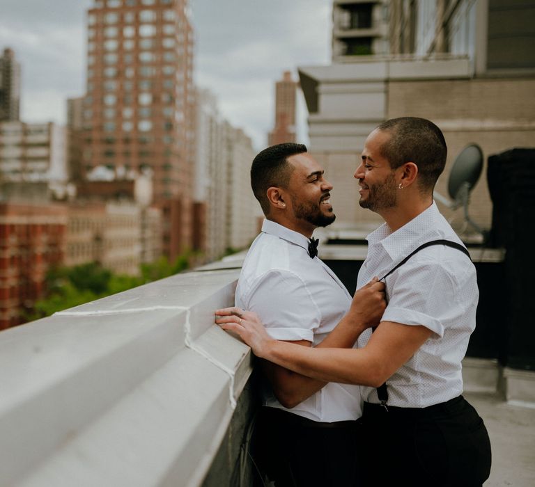 Grooms share an intimate moment at rooftop wedding