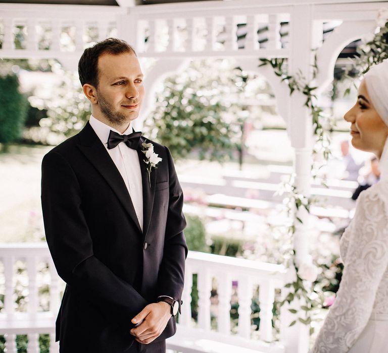 Groom tears up at bride in outdoor wedding in a white gazebo