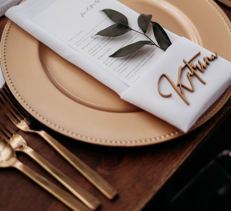 White napkins set upon gold plates with gold name placements 