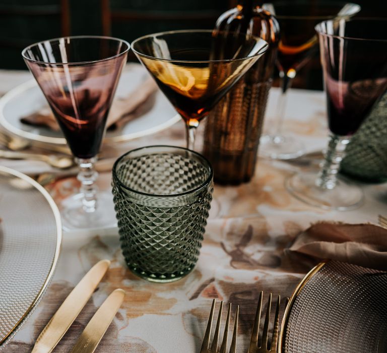 70s wedding inspiration table decor with gold cutlery and coloured glassware