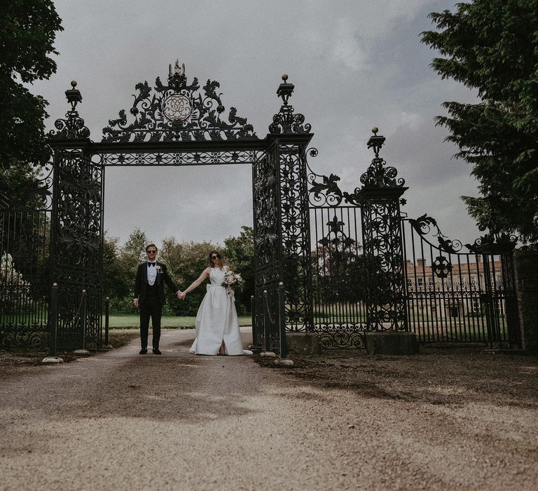 Bride & groom stand in front of black iron gate on the day of their wedding